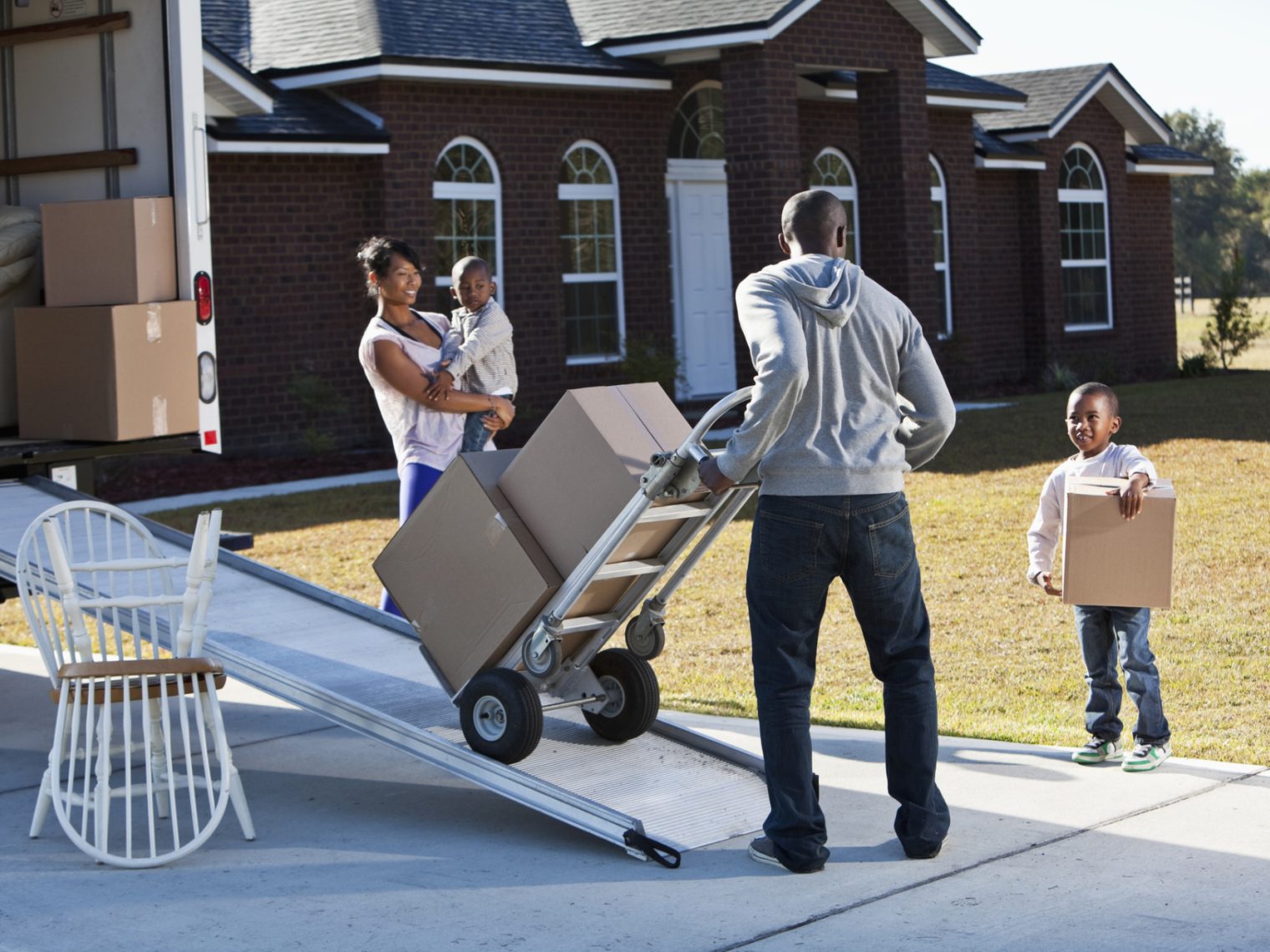 African American family moving boxes from home into vehicle.