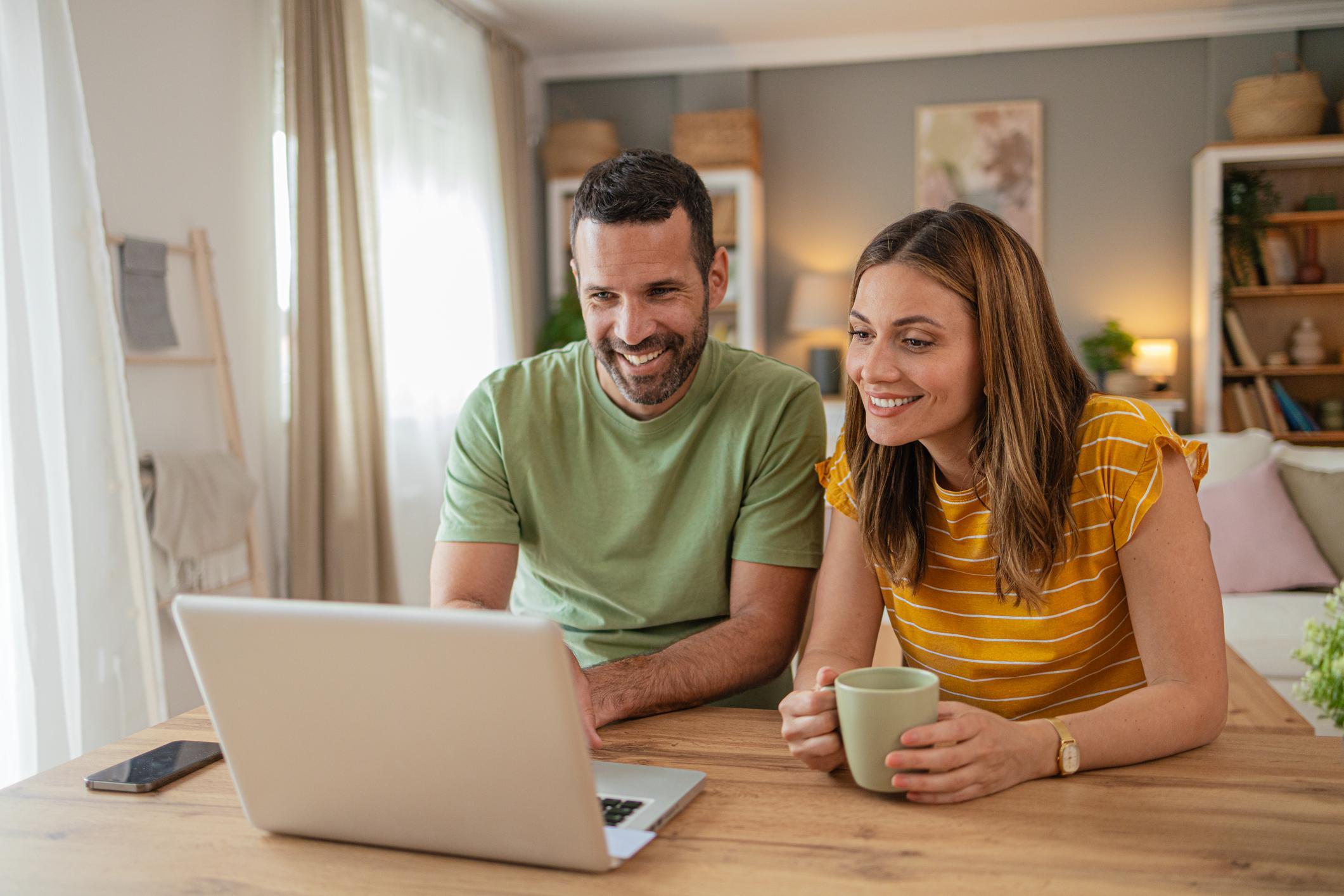 A couple sitting at their kitchen table with a laptop applying for a VA home loan.