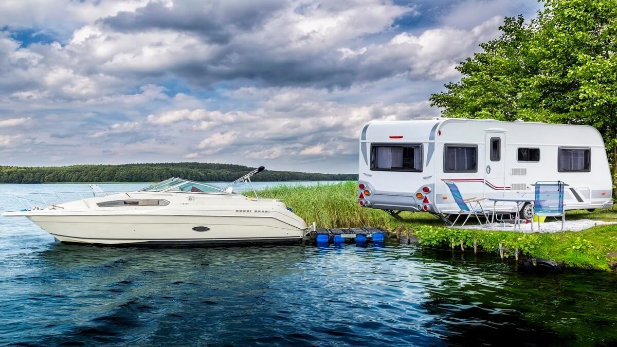 Picture of a boat in water next to a RV on land.