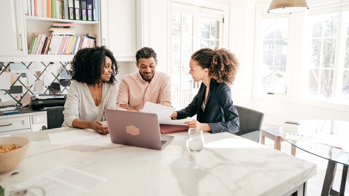 Couple talking to a real estate agent at a kitchen island.