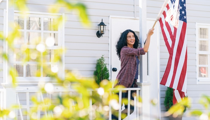 Woman hangs American flag outside of her home.