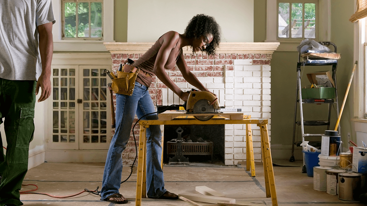 Woman using an electric saw while doing renovations in her home.